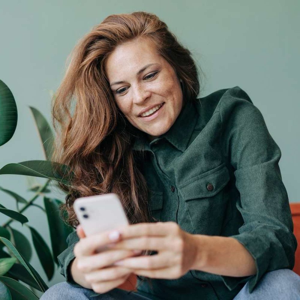 Happy smiling woman using mobile phone for online communication.